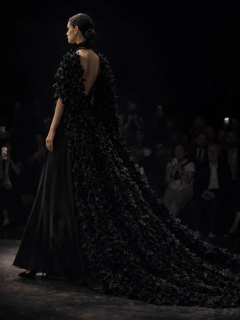Dark Couture: Seitenansicht eines schwarzen Brautkleids mit langem Cape auf dem Runway – schwarze Brautkleider Schweiz von Lafanta