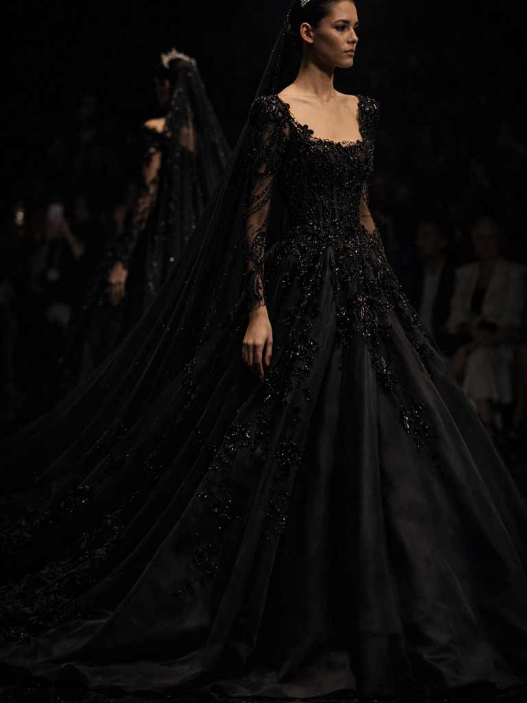 Frontansicht einer Braut im eleganten schwarzen Brautkleid mit Spitzenärmeln und langem Schleier, erhältlich bei schwarze Brautkleider Schweiz.